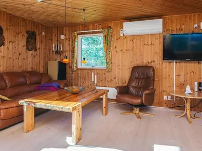 a living room with a couch and a table and a tv at Panoramic Fjord Retreat with Spa Bath in Øster Assels