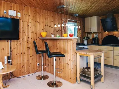 a kitchen with wooden walls and a table and chairs at Panoramic Fjord Retreat with Spa Bath in Øster Assels