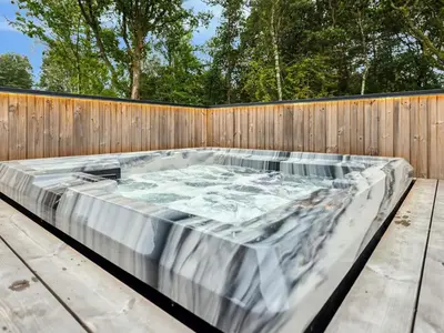 a hot tub sitting next to a wooden fence at 5 star holiday home in Skals in Skals