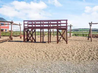 a playground with a wooden bench in the sand at 4 person holiday home in Lemvig in Lemvig