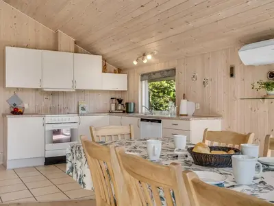 a kitchen with a table and chairs in a kitchen at Holiday Home Skrollan - 200m to the fjord by Interhome in Sindrup