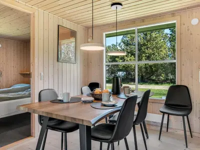 a dining room with a wooden table and black chairs at Holiday Home Rajna - 500m to the fjord by Interhome in Vestervig