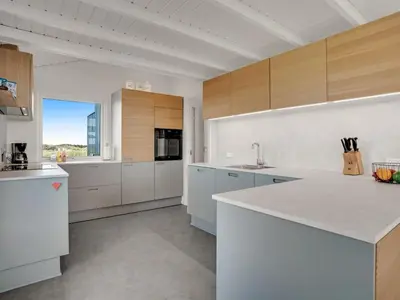 a large kitchen with white cabinets and a counter top at Holiday Home Naema - 400m from the sea by Interhome in Blokhus