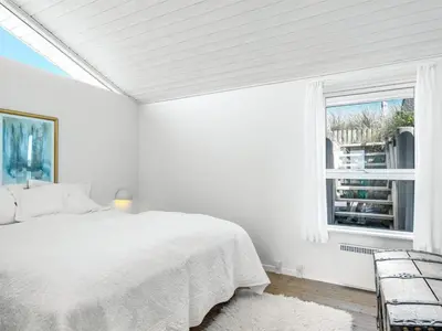 a white bedroom with a bed and a window at Holiday Home Naema - 400m from the sea by Interhome in Blokhus
