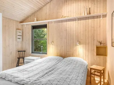 a bedroom with a bed and a wooden wall at Holiday Home Matthea - 900m from the sea by Interhome in Fjerritslev