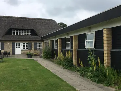 a house with a black roof and a grass yard at Danhostel Rebild in Skorping