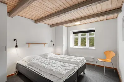 a bedroom with a bed and a window and a chair at Large Pool House With Activity Room Located In Peaceful Surroundings in Frøstrup