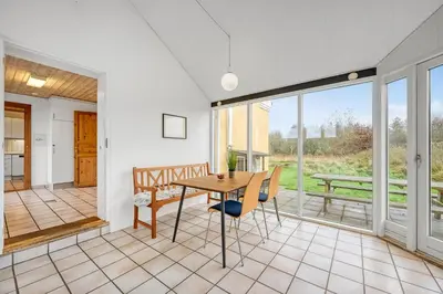 a dining room with a table and chairs and sliding glass doors at Large Pool House With Activity Room Located In Peaceful Surroundings in Frøstrup