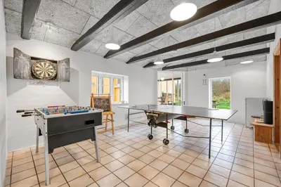 a room with two tables and a ping pong table at Large Pool House With Activity Room Located In Peaceful Surroundings in Frøstrup