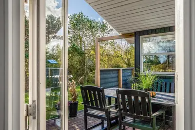 a screened porch with two chairs and a table at Lovely Spa House In Scenic Surroundings in Thyholm