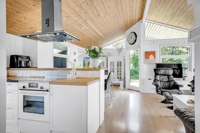 a kitchen with white cabinets and a wooden ceiling at Lovely Spa House In Scenic Surroundings in Thyholm