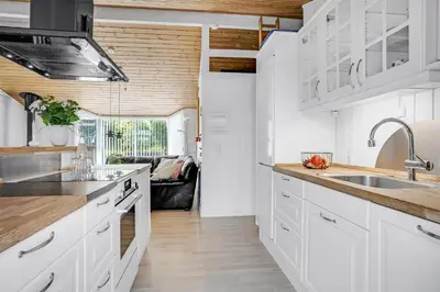 a kitchen with white cabinets and wooden ceilings at Lovely Spa House In Scenic Surroundings in Thyholm