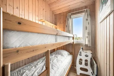 a bedroom with two bunk beds and a window at Holiday Home With Spa And Sauna, Just 200 Meters From The North Sea in Frøstrup