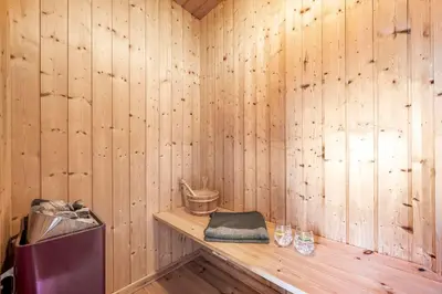 a sauna with wooden walls and a wooden shelf at Holiday Home With Spa And Sauna, Just 200 Meters From The North Sea in Frøstrup