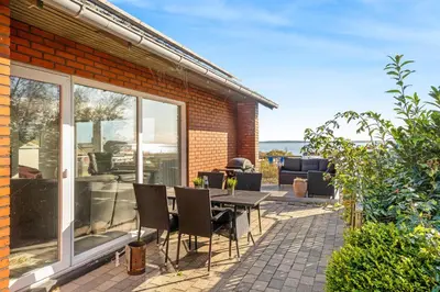 a patio with a table and chairs in front of a house at Large Holiday Home With A View Of The Fjord in Thyholm
