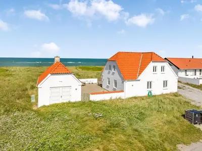 two white houses with orange roofs on a grassy hill at Pool And Activity House With A Fantastic View Of The North Sea in Frøstrup