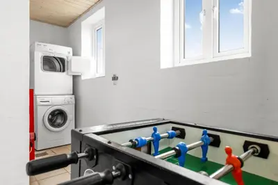 a ping pong table in a room with a washer at Pool And Activity House With A Fantastic View Of The North Sea in Frøstrup