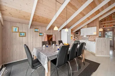 a dining room with a table and black chairs at Pool House With Spa And Sauna, 200 Meters From The North Sea in Frøstrup