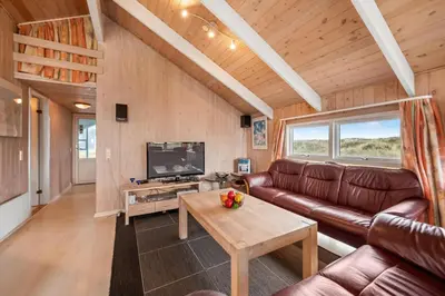 a living room with a couch and a tv at Pool House With Spa And Sauna, 200 Meters From The North Sea in Frøstrup