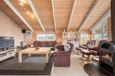 a living room with leather furniture and a fireplace at Pool House With Spa And Sauna, 200 Meters From The North Sea in Frøstrup
