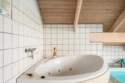 a bath tub in a bathroom with white tiles at Pool House With Spa And Sauna, 200 Meters From The North Sea in Frøstrup
