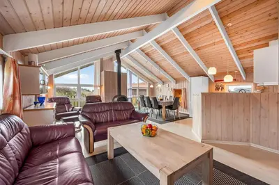 a living room with leather furniture and a table at Pool House With Spa And Sauna, 200 Meters From The North Sea in Frøstrup