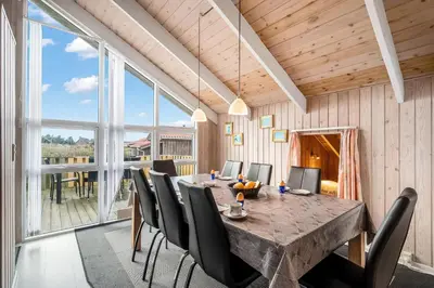 a dining room with a large wooden table and chairs at Pool House With Spa And Sauna, 200 Meters From The North Sea in Frøstrup