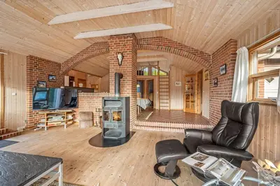 a living room with a fireplace and a brick wall at Cozy And Spacious Holiday Home Near Torup Strand Close To The North Sea in Fjerritslev