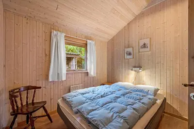 a bed in a room with a wooden wall at Cozy And Spacious Holiday Home Near Torup Strand Close To The North Sea in Fjerritslev
