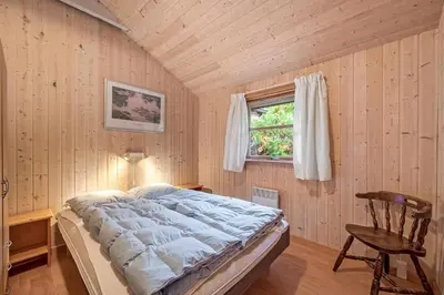 a bedroom with a bed and a chair and a window at Cozy And Spacious Holiday Home Near Torup Strand Close To The North Sea in Fjerritslev