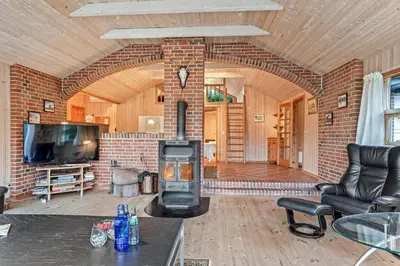 a living room with a brick fireplace and a tv at Cozy And Spacious Holiday Home Near Torup Strand Close To The North Sea in Fjerritslev