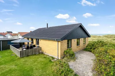 a house with a black roof and a patio at Lovely Holiday Home With Panoramic Views Of The North Sea in Frøstrup