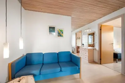 a blue couch in a room with a bedroom at Lovely Holiday Home With Panoramic Views Of The North Sea in Frøstrup