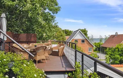 a wooden deck with wicker chairs and an umbrella at Amazing Home In Hurup Thy in Doverodde