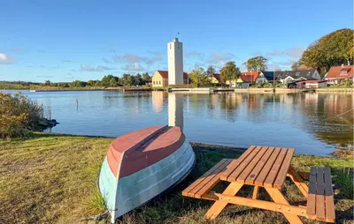 a boat sitting on the side of a lake with a bench at Amazing Home In Hurup Thy in Doverodde
