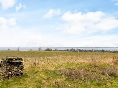 a pile of wood sitting in a field at 8 person holiday home in Roslev in Roslev