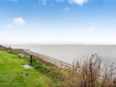a grassy hill next to a body of water at Holiday Home Næwe - 10m to the fjord by Interhome in Roslev