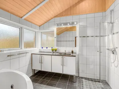 a white bathroom with a sink and a shower at Holiday Home Næwe - 10m to the fjord by Interhome in Roslev
