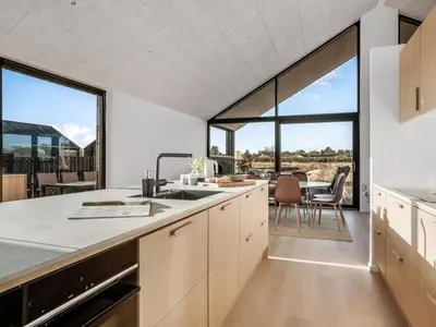 an open kitchen with large windows and a dining room at Holiday Home Stenkil - 1-2km from the sea by Interhome in Løkken