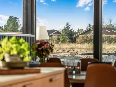 a dining room with a view of a field through a window at Holiday Home Stenkil - 1-2km from the sea by Interhome in Løkken