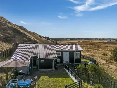 a small house with a table and an umbrella at Holiday Home Sella - 600m from the sea by Interhome in Blokhus