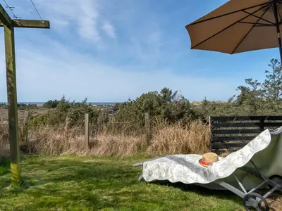 a teddy bear sitting in a chair under an umbrella at Holiday Home Sella - 600m from the sea by Interhome in Blokhus