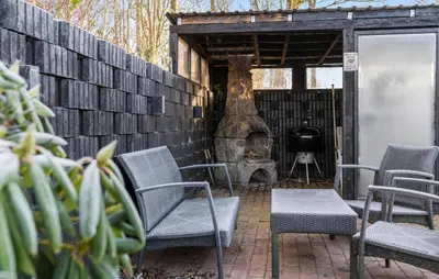 a patio with chairs and a wood fired oven at Pet Friendly Home In Karby in Karby