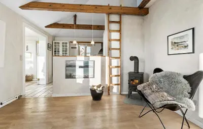 a living room with a wood stove and a chair at 3 Bedroom Cozy Home In Nibe in Nibe