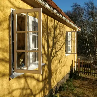a window on the side of a yellow house at Charming Summer House From 1945 in Sønder Ydby