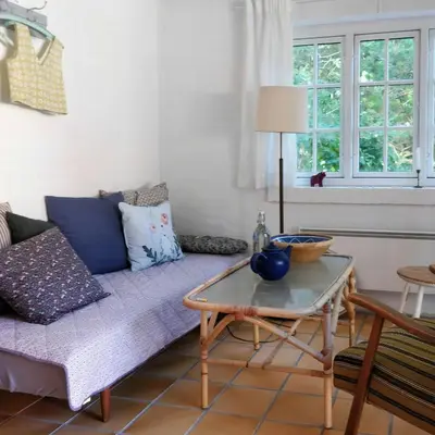 a living room with a couch and a table at Charming Summer House From 1945 in Sønder Ydby