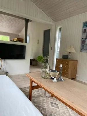 a living room with a wooden table and a television at A Gem In The Woods Close To The North Sea in Rødhus
