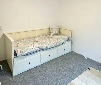 a small bed in a room with a white wall at Familievenligt Hus Nær Tranum Klitplantage in Pandrup