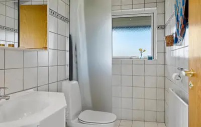 a bathroom with a toilet and a sink and a window at Amazing Home In Lemvig in Lemvig