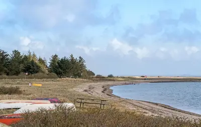 a beach with a bench next to a body of water at Amazing Home In Lemvig in Lemvig